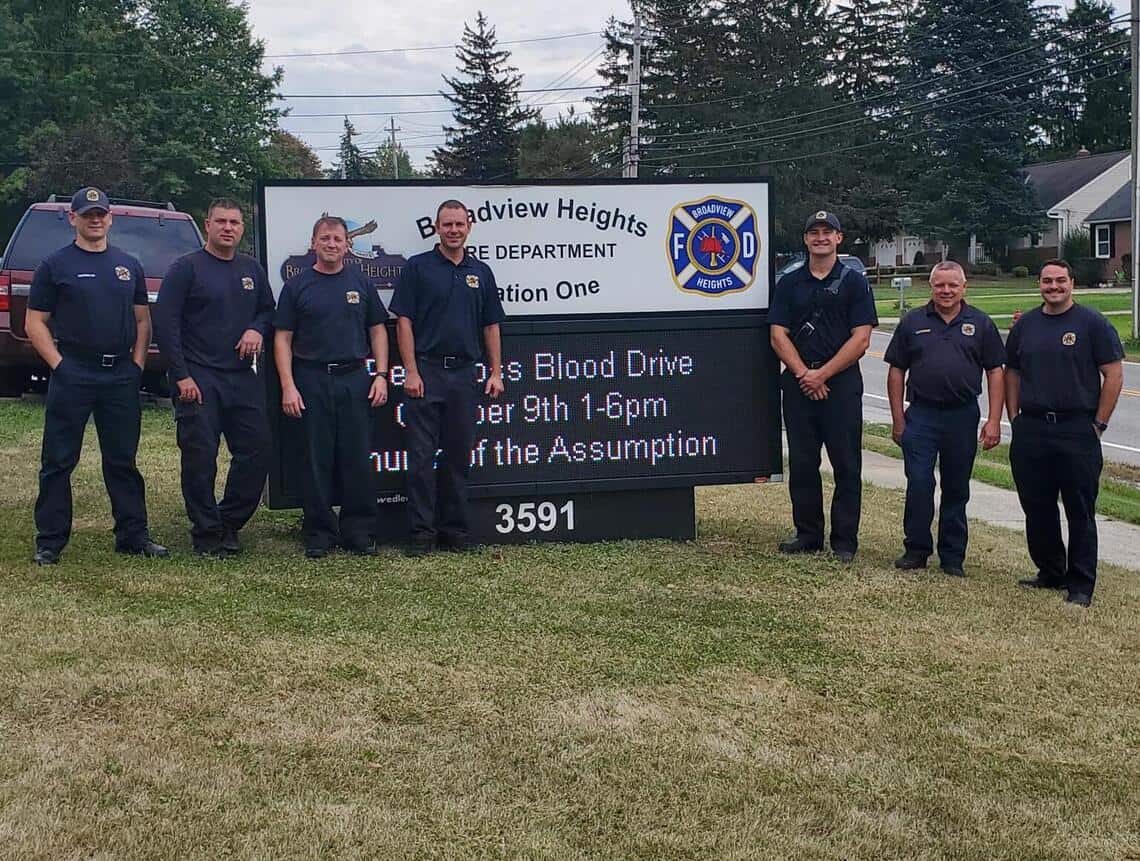 group of firefighters who support ACBC of Northeast Ohio in front of their department sign